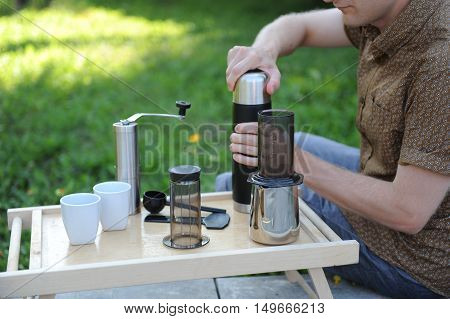 Man making fresh aeropress coffee in nature