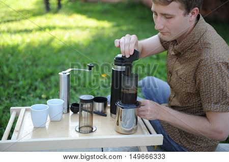 Man making fresh aeropress coffee in nature