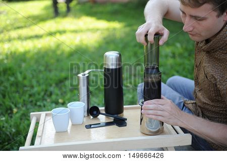 Man making fresh aeropress coffee in nature