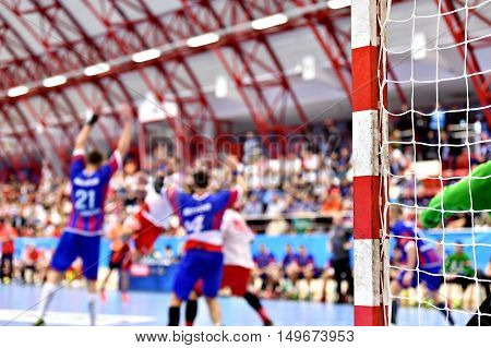 Handball match scene with goalpost and players in the background