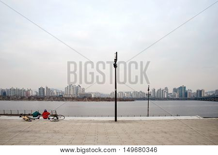 SEOUL SOUTH KOREA JANUARY 06: People sitting by the famous Han river which is a landmark where many go to cycle along the river January 06th 2016 in Seoul