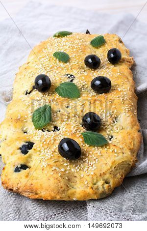 Italian bread with olive garlic and herbs. Homemade traditional Italian bread focaccia on the linen napkin.