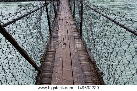 Rustic old wooden bridge across turquoise river