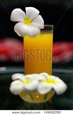 a freshly squeezed fresh orange juice close-up with a Magnolia blossoms on the glas