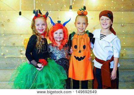 Happy group of witch children pirate and demons during Halloween party playing around the table with pumpkins