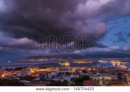 Sunset in the Port of Messina in Sicily Italy. Clouds and sunset light with night illumination.