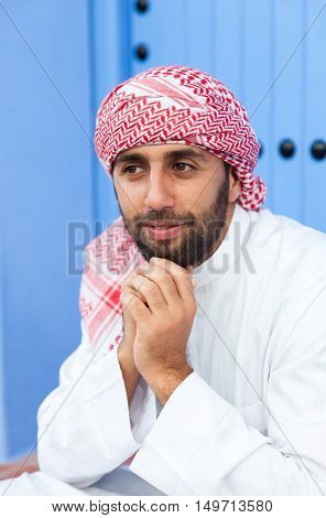 Young smiling handsome arabic man wearing traditional clothes