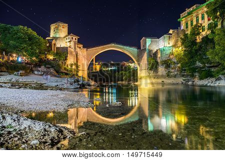 A view of the Mostar skyline at night towards the Old Bridge (Stari Most). Buildings and the River Neretva can be seen.