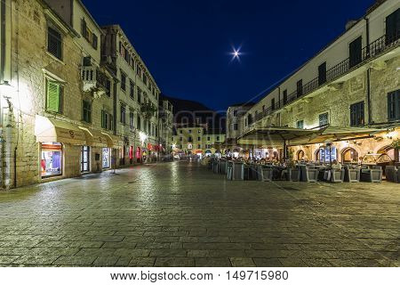 KOTOR MONTENEGRO - 13TH AUGUST 2016: Views along streets of Old Town Kotor at night. The outside of buildings restaurants and people can be seen.