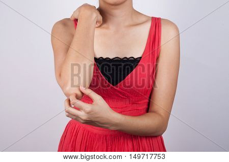 Woman scratching her elbow on  a white background