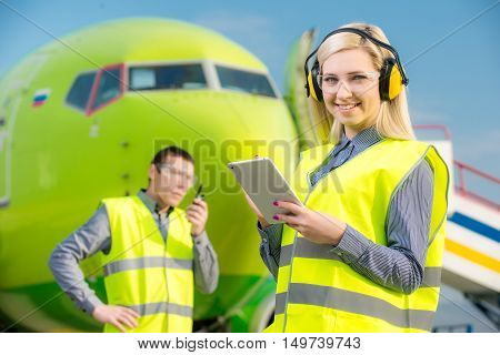 Aircraft workers with radio standing in front of a commercial airliner