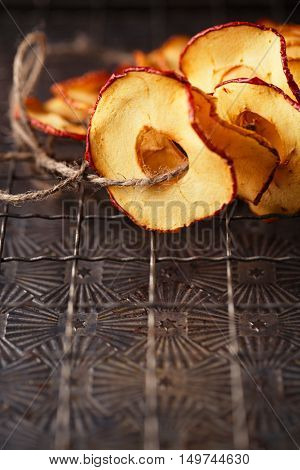 Dried apple slices hanging on string with dark metal backdrop