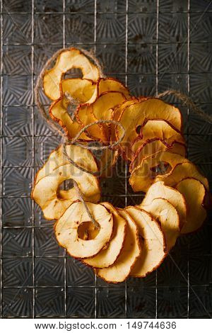 Dried apple slices hanging on string with dark metal backdrop