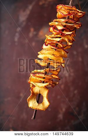 Dried apple slices hanging on string with dark metal backdrop