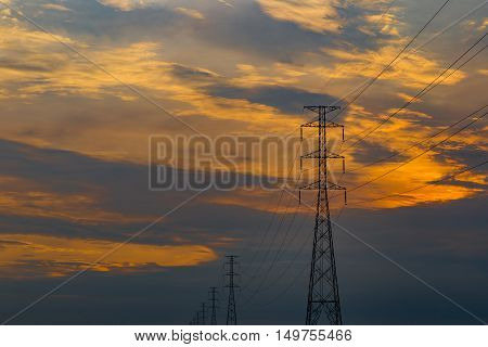 High voltage electrical transmission line and tower in rice field during sunset