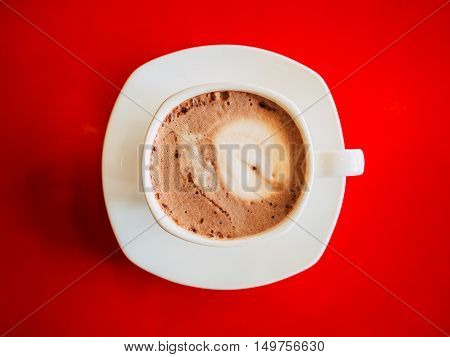 Top view of white coffee cup on red table.