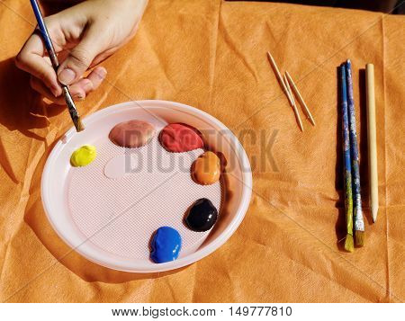 Improvised palette from a plastic platel with the paints brush and pencil
