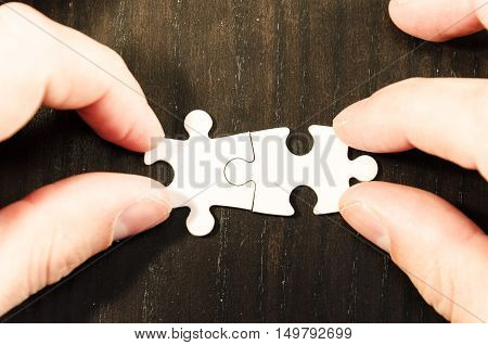 white jigsaw/puzzle whit one gap over black wooden table background symbol of problem solving