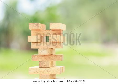 Close up hand holding blocks wood game (jenga) on blurred green background. Risk concept
