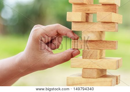 Hand Holding Blocks Wood Game (jenga) On Blurred Green Background. Risk Concept