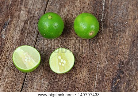 whole and sliced lime on wooden table top view