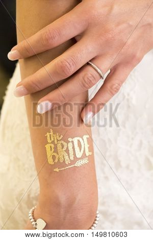 female hand show wedding ring and text bride glitter golden tattoo