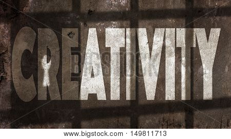 Creativity Written On A Wall With Jail Bars Shadow.