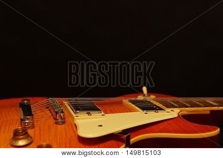 Solid body electric blues guitar closeup on the black background with plenty of copy space. Selective focus.