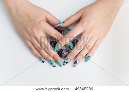 Closeup of woman nails with creative purple and green manicure. Fluorinit print. Copy space.