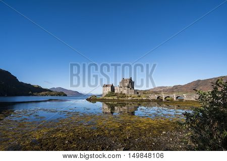 Typical Scottish scene of Eilean Donan Castle beautiful 13th century fortification at Dornie Kyle of Lochalsh in the Scottish Highlands with clear blue sky and reflections