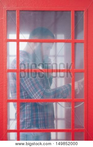 bearded man calling from a red english telephone booth