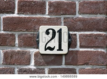 Enameled house number twenty one on a red brick wall