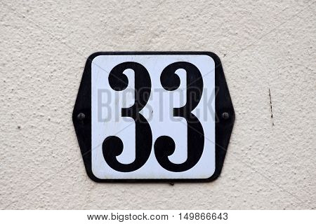 Enamelled house number thirty-three sign on a wall