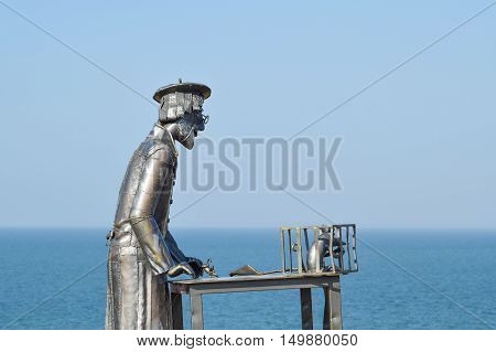 Statue Of A Furrier From Metal With A Rat In A Cage
