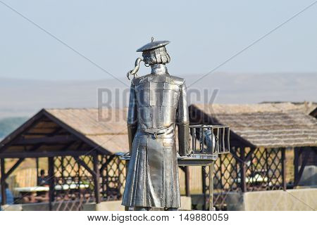 Statue Of A Furrier From Metal With A Rat In A Cage