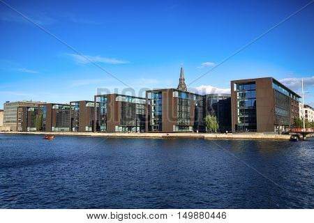 COPENHAGEN DENMARK - AUGUST 16 2016: Beautiful view on Copenhagen waterfront modern buildings and behind medieval church tower in Copenhagen Denmark on August 16 2016.