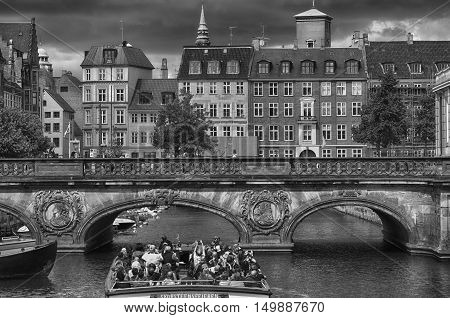 COPENHAGEN DENMARK - AUGUST 14 2016: Black and white photo view of canal boat with tourist and old bridge from bridge Prinsens Bro in Copenhagen Denmark on August 14 2016.