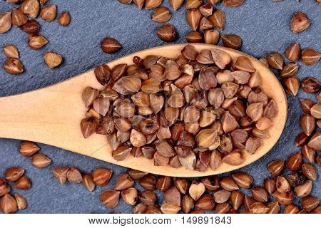 Buckwheat in a wooden spoon on slate