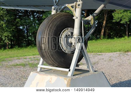 Right tire of Douglas Dakota DC-3 C-47 WWII plane exhibit in local forest positioned on stone and steel foundations