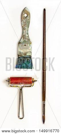A photo of two brushes and a brayer, with paint on them, on white background