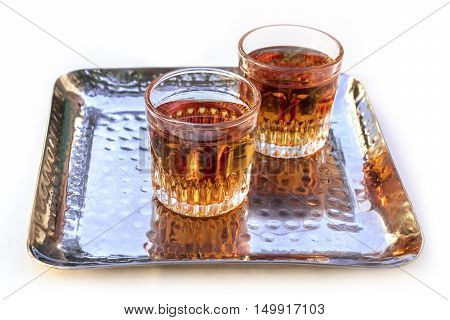 A photo of two glasses of Pacharan, typical sloe flavored Spanish liquor, on a tray, isolated on white