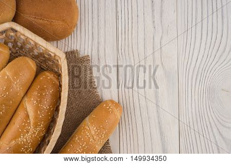 Buns in a wicker basket on old wooden table. Top view.