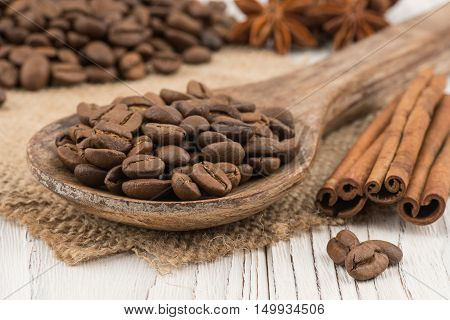 Coffee beans in a wooden spoon on old wooden table. Selective focus.