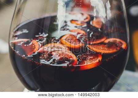 Making hot alcohol, mulled wine for sale at country fair. Glintwine from red wine with citrus and cloves in big glass, Closeup