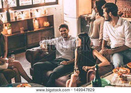 Spending time with friends. Top view of cheerful young people enjoying food and drinks while spending nice time in cofortable chairs at home together