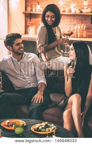 Friendly talk. Cheerful young people enjoying food and drinks while spending nice time in cofortable chairs at home together