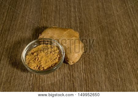 Raw ginger and its powder on a wooden background