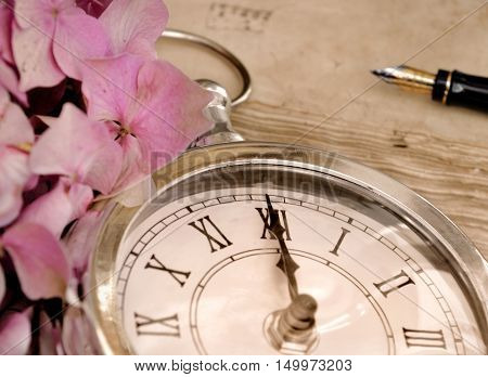 midnight on a vintage clock with pink flower petal and a foutain pen