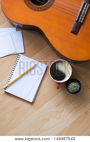 Concept of Music Musician and Song Writer. Guitar CactusCup of Coffee notebook and pencil with empty photo on wooden table.Copy Space