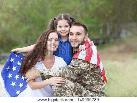 US army soldier with family and USA flag in park